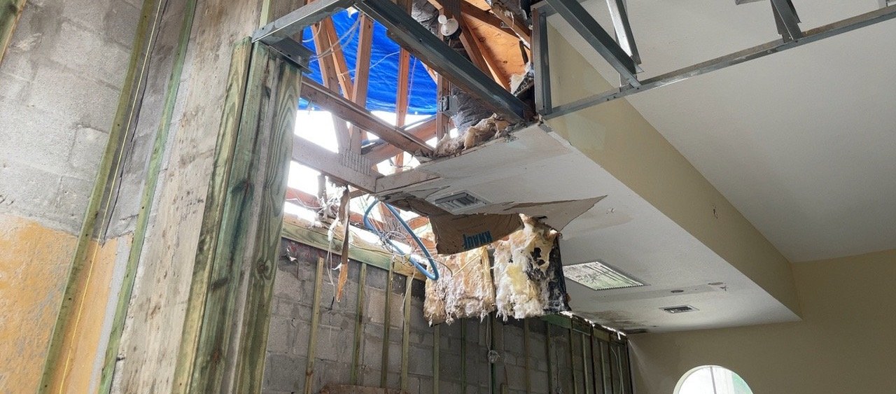Structural repair in progress — exposed roof framing, opened ceiling and displaced insulation.