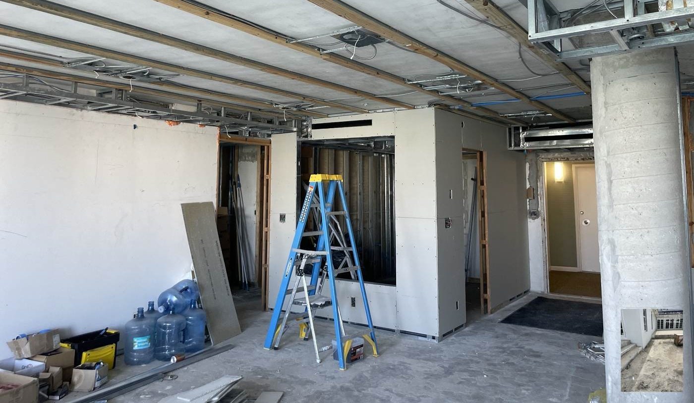 Interior build-out in progress — drywall partitions, ceiling framing and a step ladder.